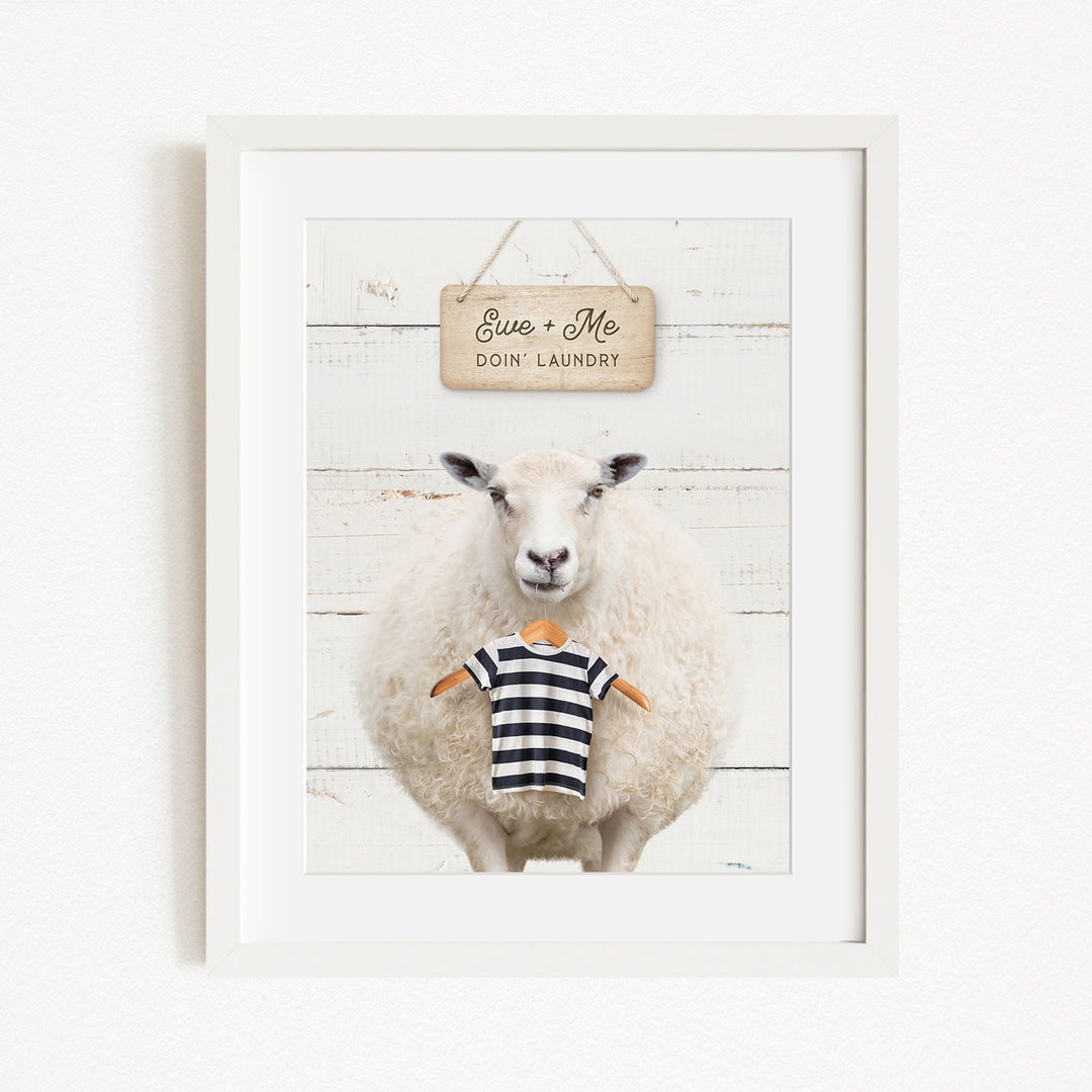 A framed image of a sheep wearing a striped shirt, with a sign above it that says "Euse + Me Doin Laundry".