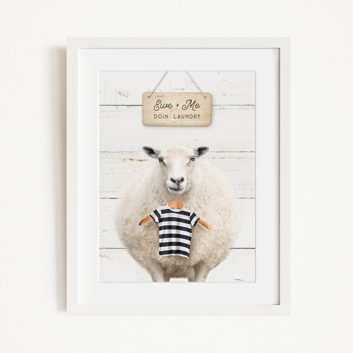A framed image of a sheep wearing a striped shirt, with a sign above it that says "Euse + Me Doin Laundry".