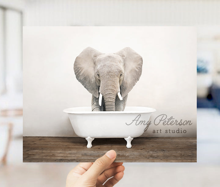 a person holding up a card with an elephant in a bathtub