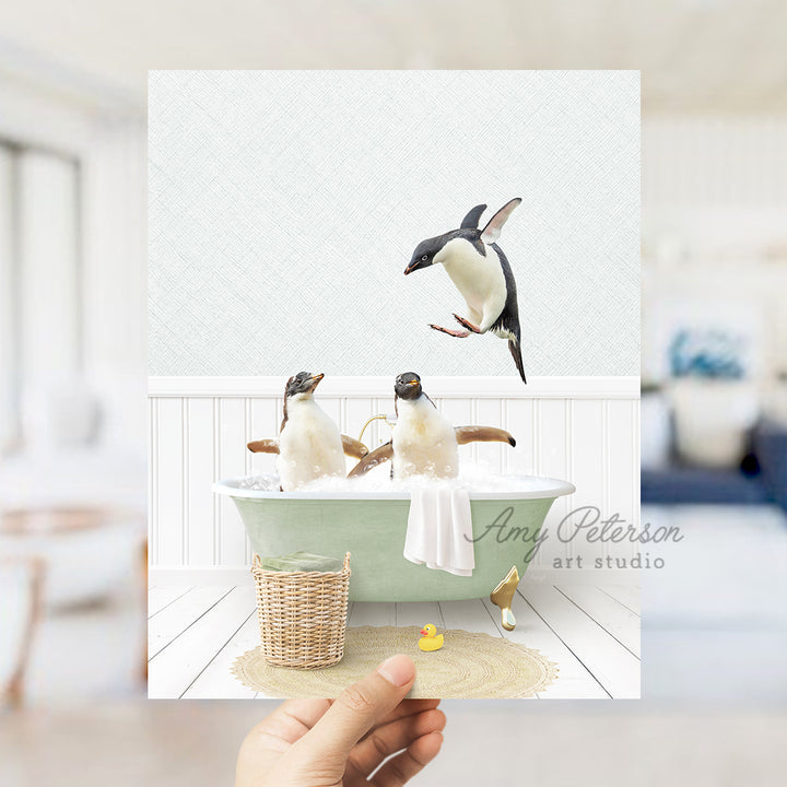 a hand holding up a card with penguins in a bathtub