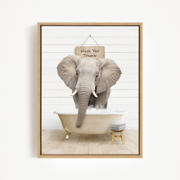 A gray elephant standing in a bathtub filled with water, with a sign above it that says "Wash Yer Trunk".