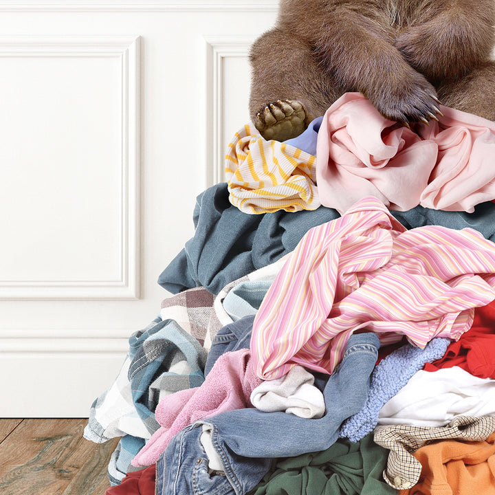 a brown bear sitting on top of a pile of clothes