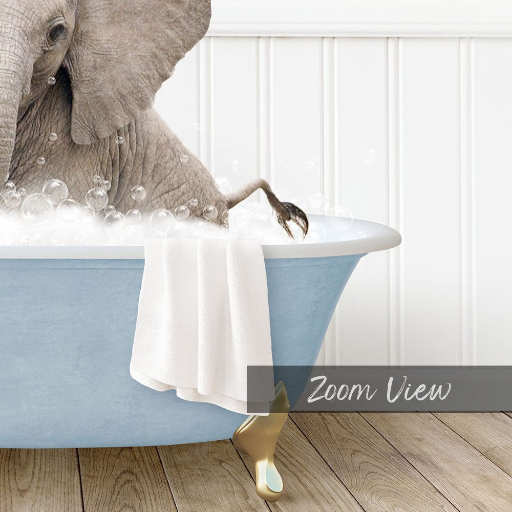 A large elephant is sitting in a blue bathtub filled with bubbles, with its trunk raised in the air.