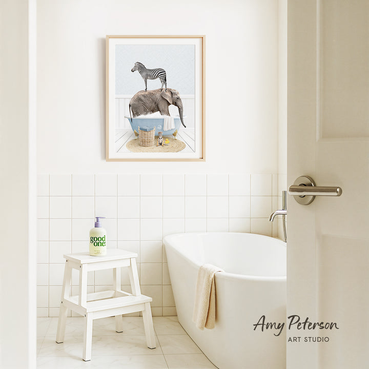 a bathroom with a white bathtub, a stool, and a framed illustration of a zebra standing on a pile of towels.