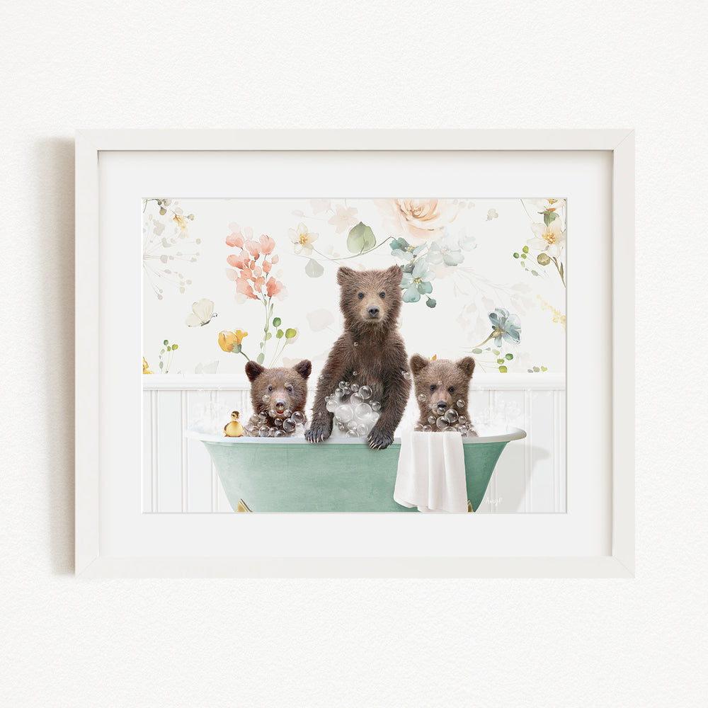 A framed image depicting three bears sitting in a green bathtub, with one bear standing on the edge of the tub and the other two bears sitting inside the tub.