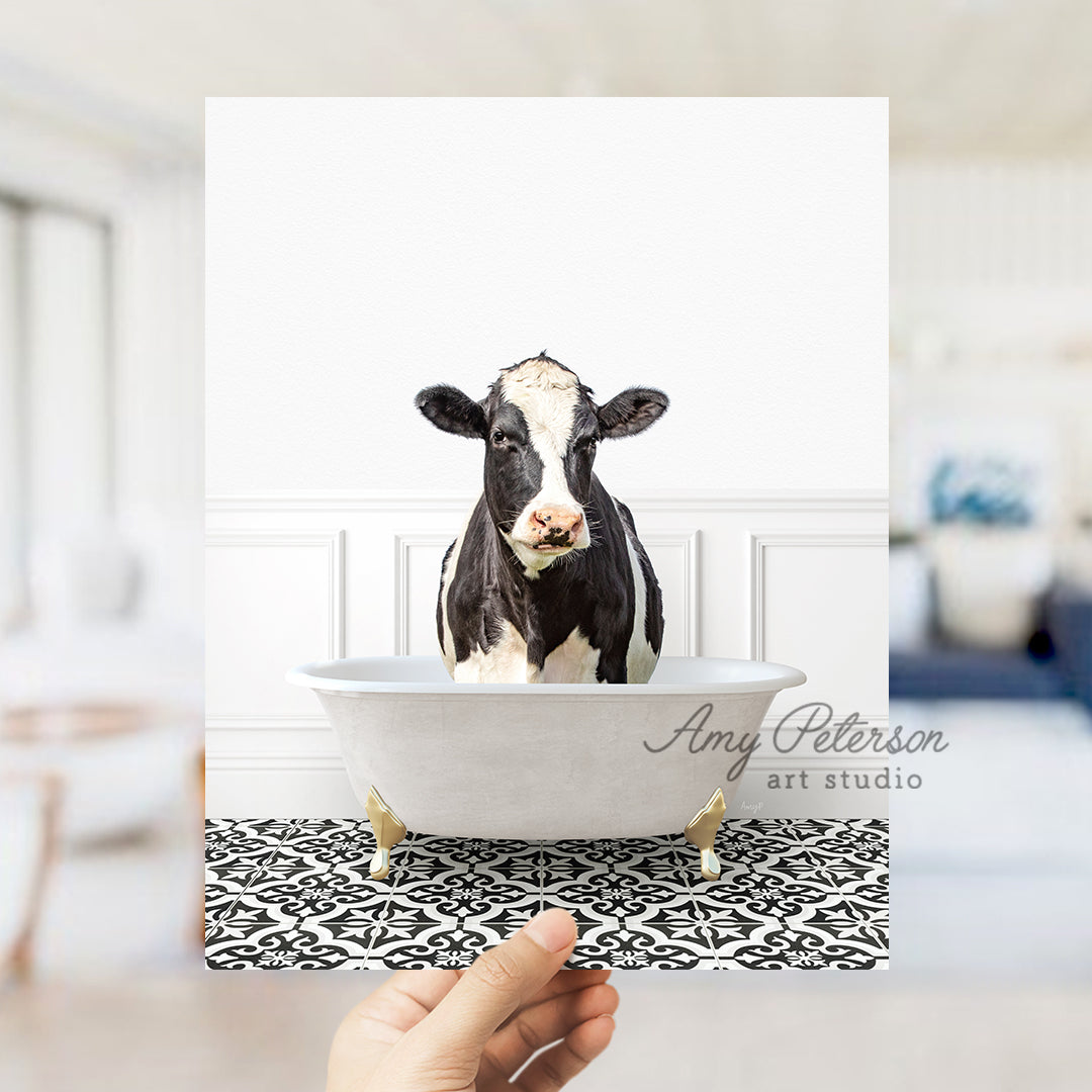 a hand holding a card with a picture of a cow in a bathtub