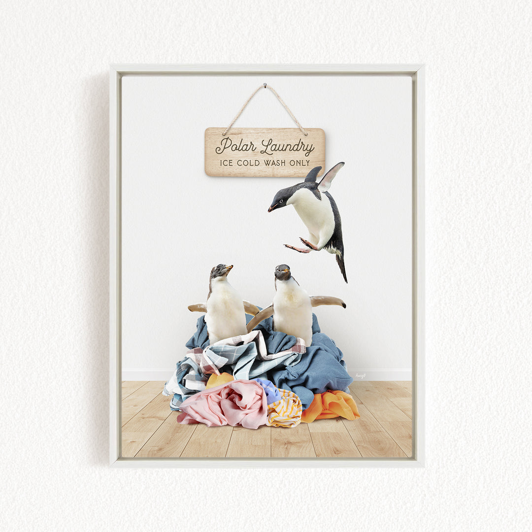 A framed image depicting two penguins standing on a pile of clothes, with a sign above them that reads "Polar Laundry - Ice Cold Wash Only".