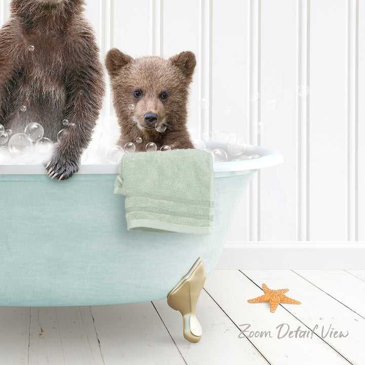 A baby bear sitting in a bathtub filled with bubbles, with a towel and starfish nearby.