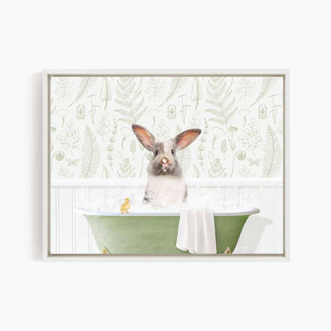 A white rabbit sitting in a green bathtub, surrounded by a white towel and a yellow rubber duck.