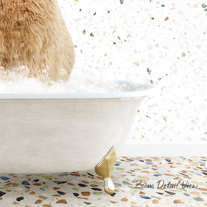 A fluffy brown cat is sitting in a white bathtub filled with bubbles, with a mosaic floor in the background.