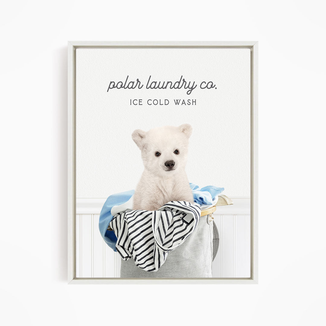 A white polar bear sitting in a laundry basket filled with clothes, with the text "polar laundry co. ICE COLD WASH" displayed above the image.