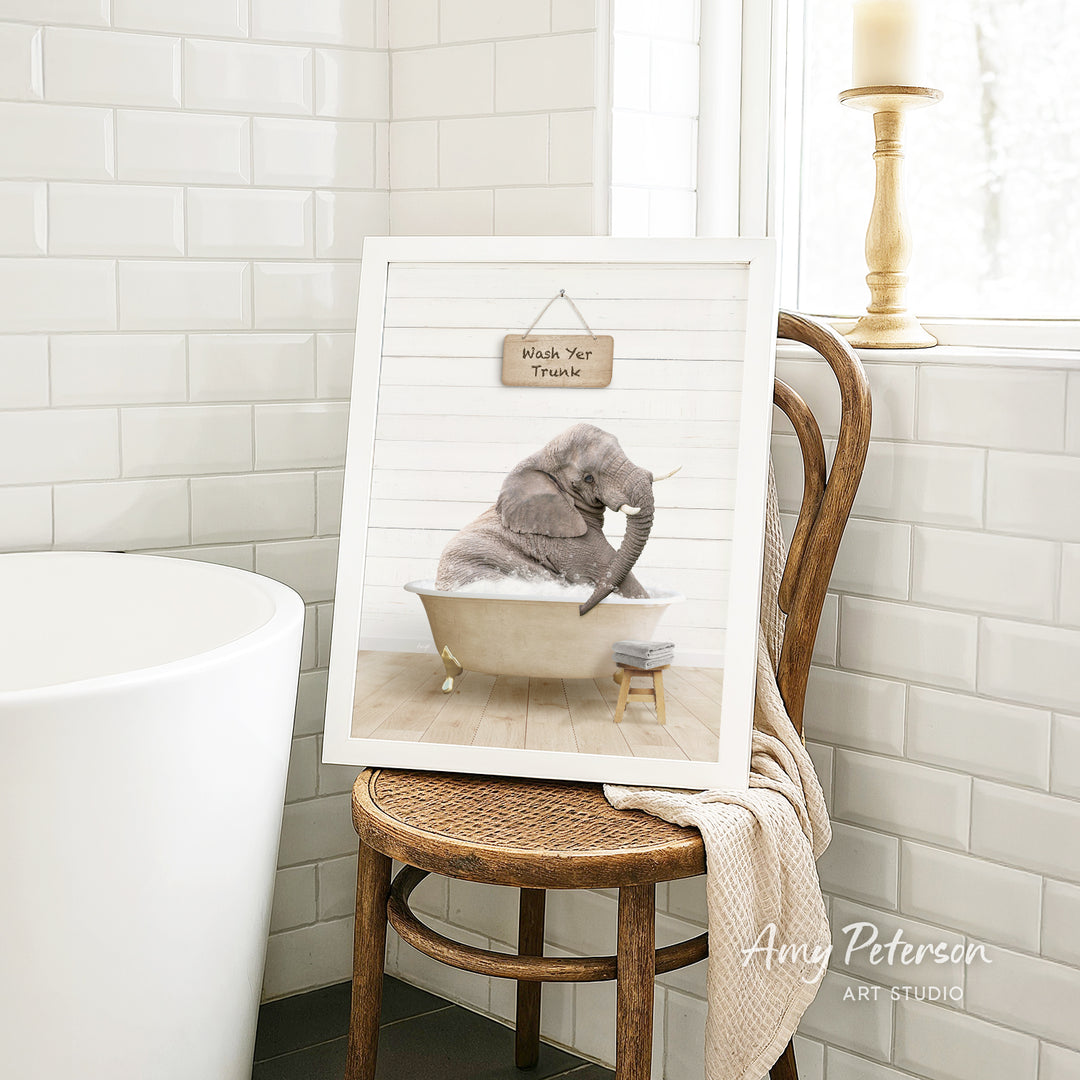 A framed image of a gray elephant sitting in a bathtub, with a sign above it that says "Hush Yer Trunk".