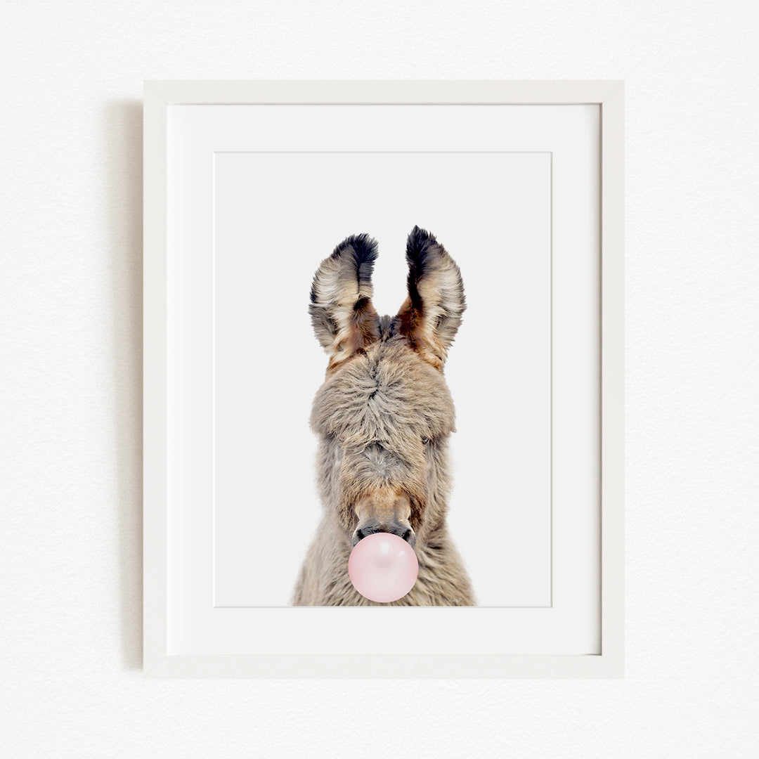 A donkey with its head tilted upwards and a pink bubble blowing in its mouth.