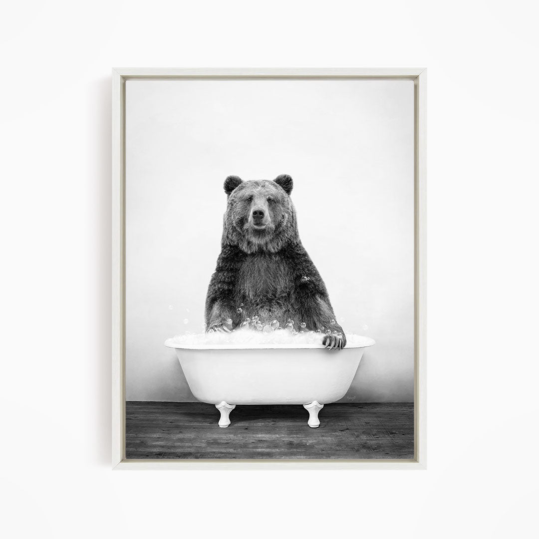 A black and white image of a bear sitting in a bathtub filled with water.