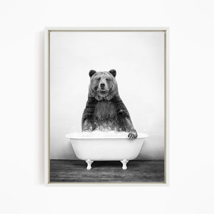 A black and white image of a bear sitting in a bathtub filled with water.