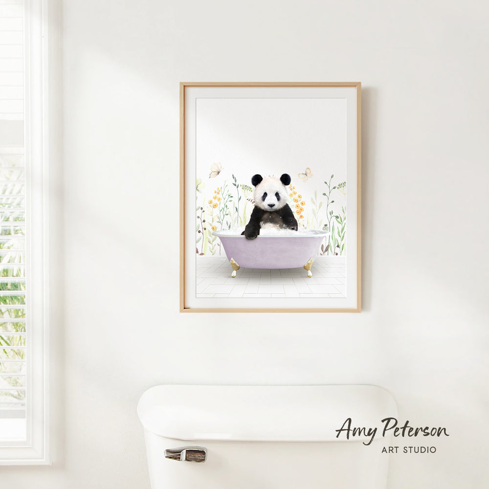 A framed print of a panda sitting in a bathtub is hanging on a white wall.