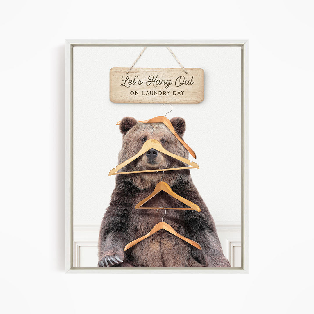 A framed image of a bear sitting on a chair with a sign above it that says "Let's Hang Out on laundry day".
