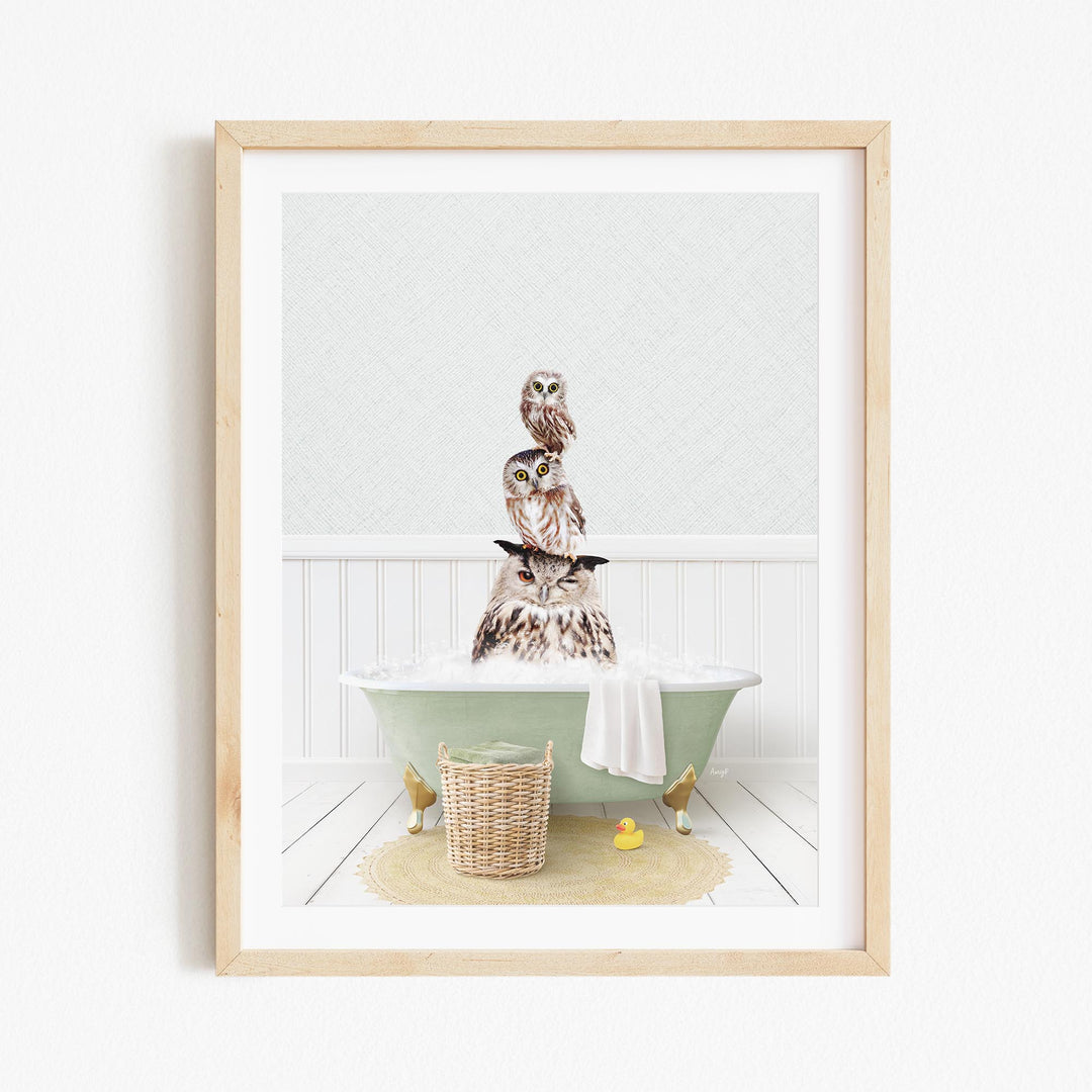 A framed image depicting a group of owls sitting in a bathtub, with a basket of rubber ducks and a towel nearby.