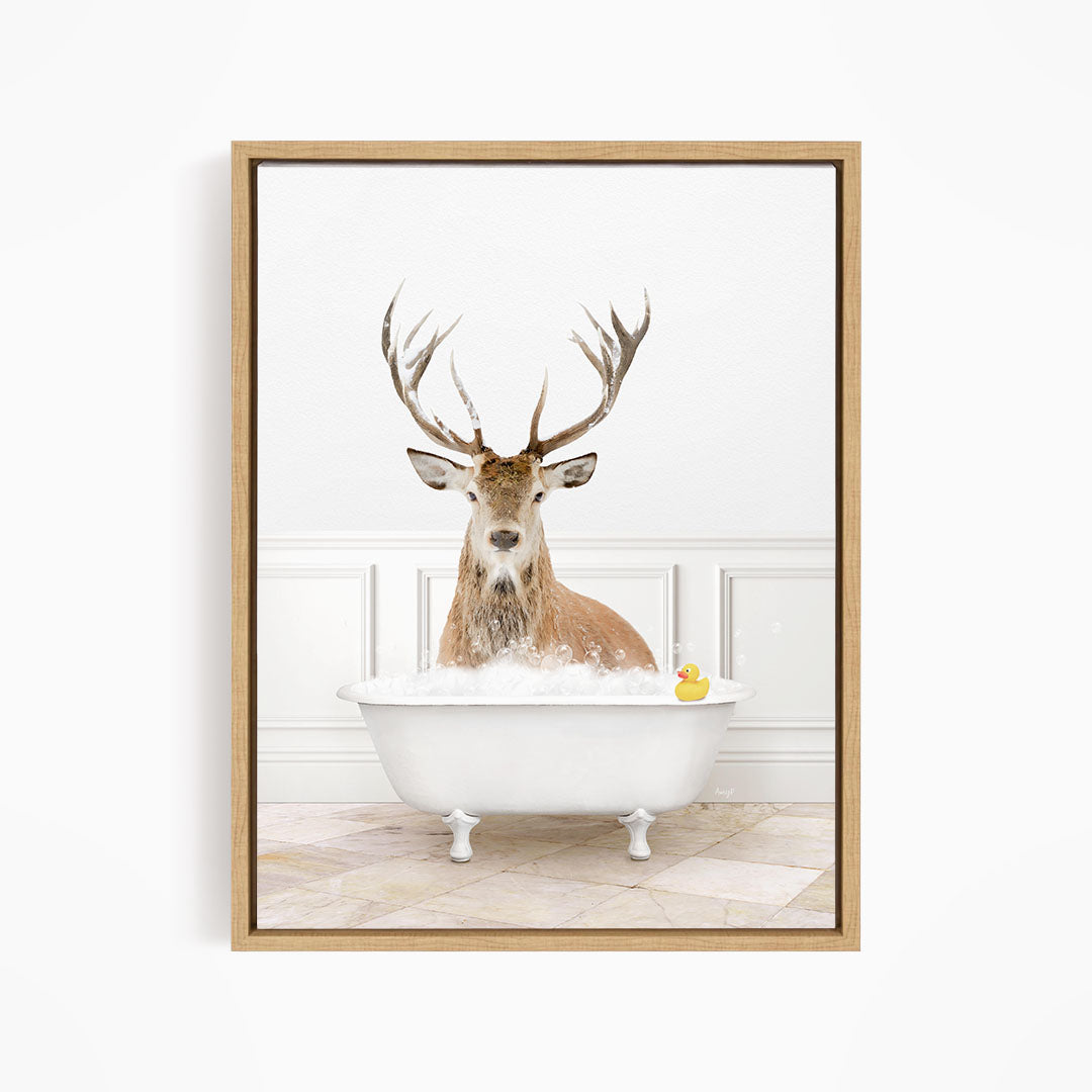 A deer with large antlers is sitting in a white bathtub filled with bubbles, with a rubber duck floating in the water.