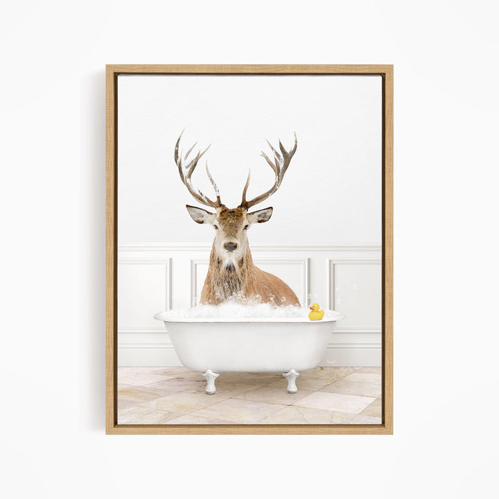 A deer with large antlers is sitting in a white bathtub filled with bubbles, with a rubber duck floating in the water.