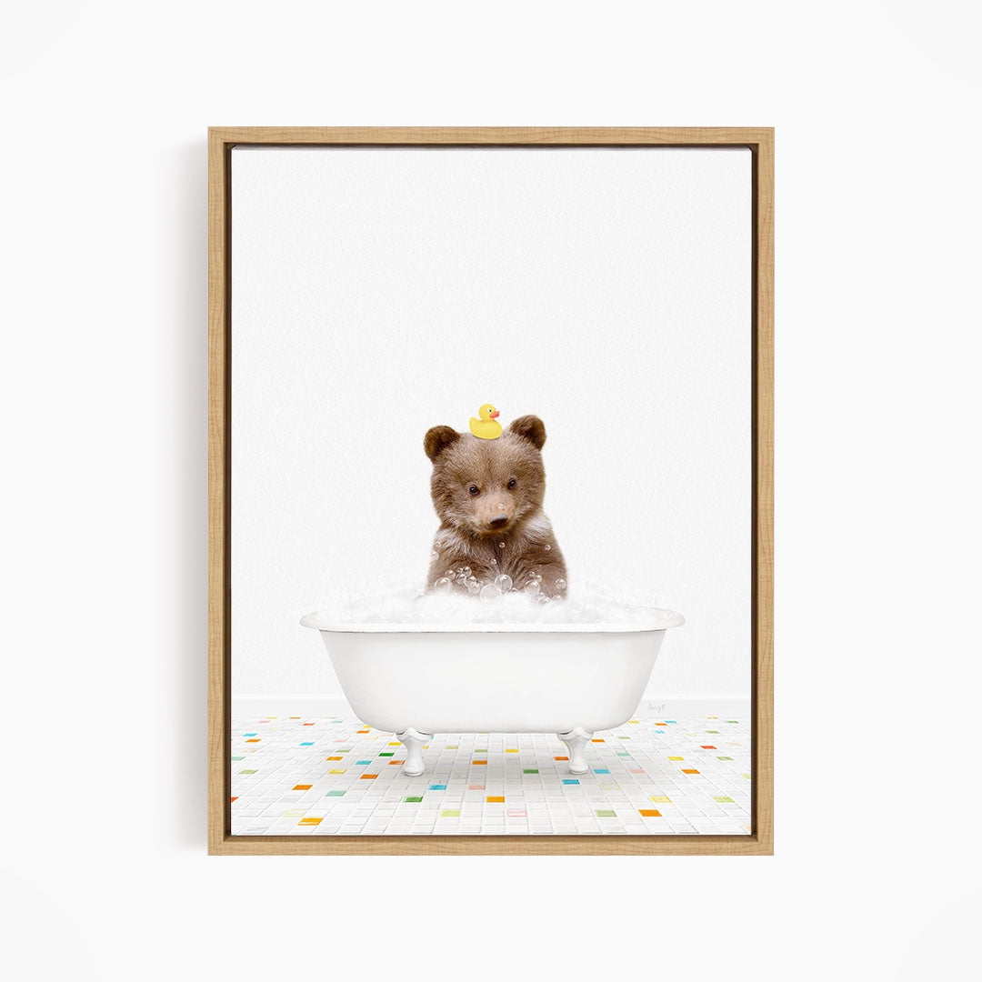 A cute brown bear sitting in a white bathtub filled with bubbles, wearing a yellow rubber duck hat.