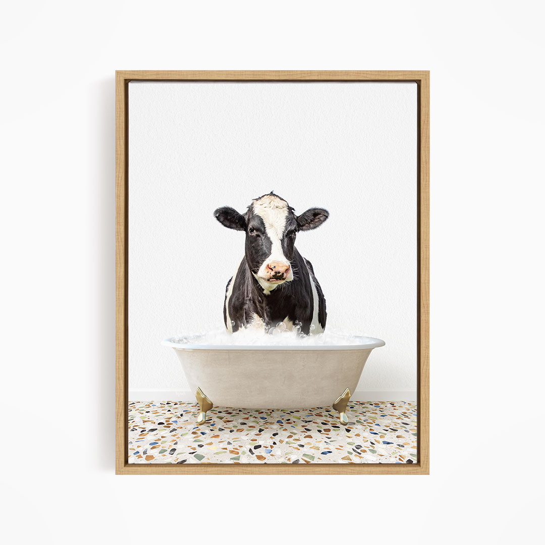 A black and white cow standing in a white bathtub filled with water, creating a whimsical and humorous scene.