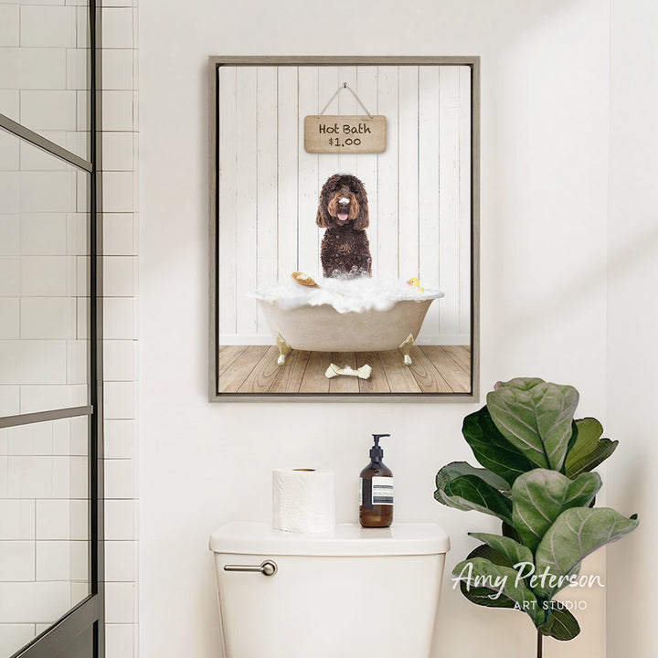 A framed image of a dog sitting in a bathtub, with a sign above it that says "Hot Bath is Fun". The image is displayed above a white toilet in a bathroom setting.