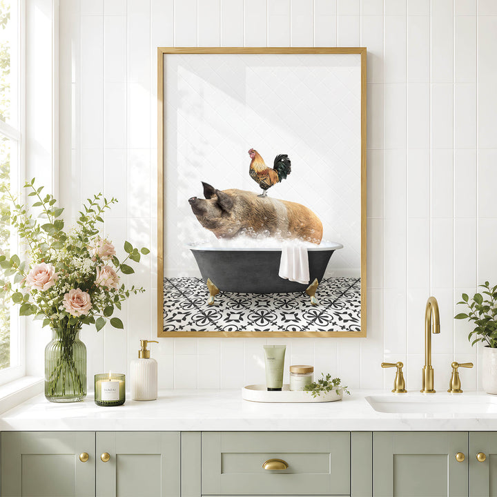 A framed image of a pig sitting in a bathtub, with a rooster perched on its back, is displayed on a white tiled wall above a bathroom counter with various toiletries and a vase of flowers.