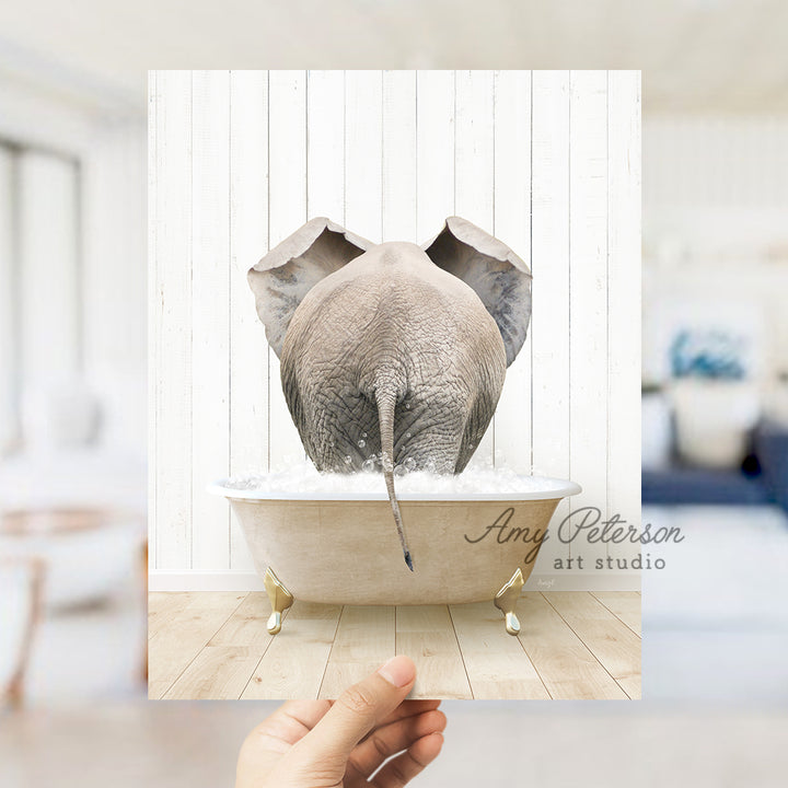 a hand holding a photo of an elephant in a bathtub