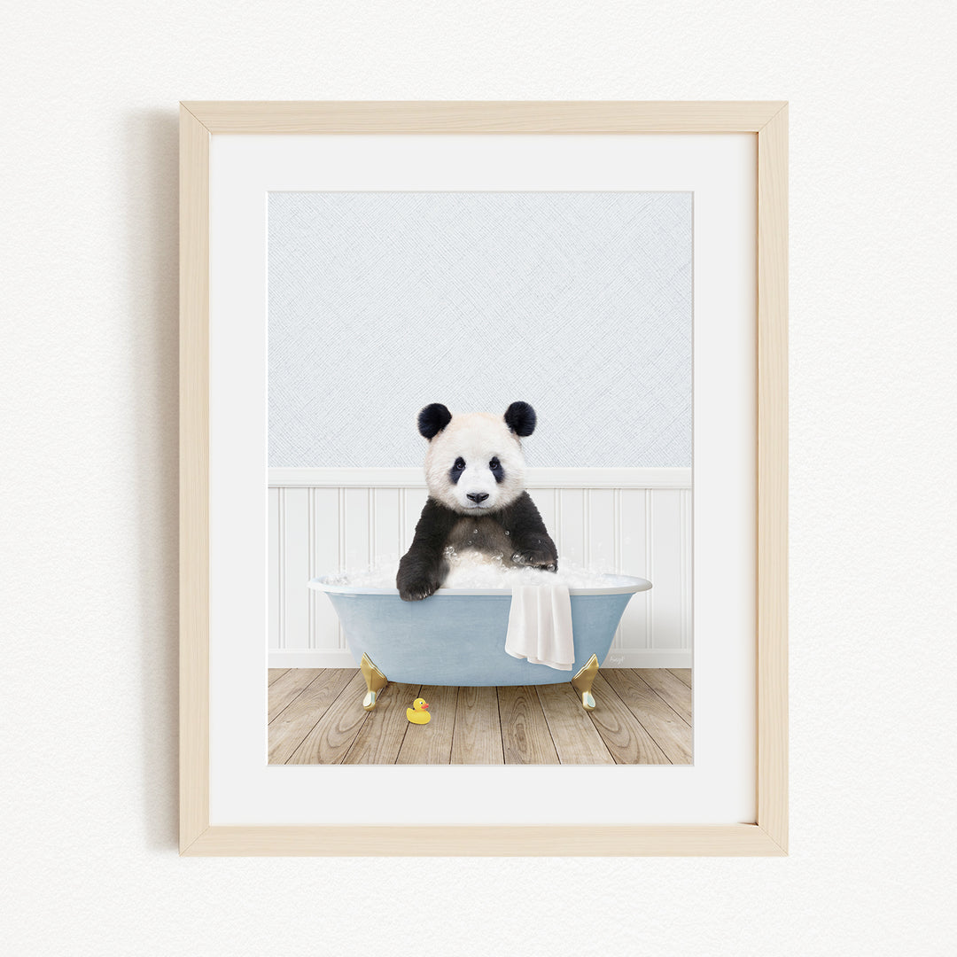 A panda bear sitting in a blue bathtub, surrounded by yellow rubber duckies, in a white framed picture.