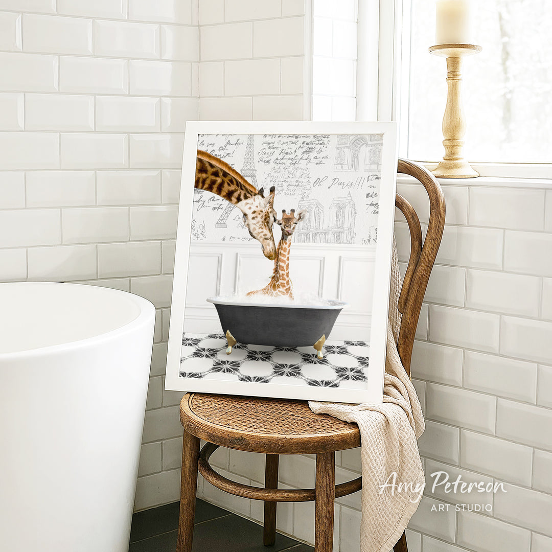A framed image of two giraffes sitting in a bathtub, with one giraffe appearing to be bathing the other. The image is displayed on a wooden chair in a bathroom setting.
