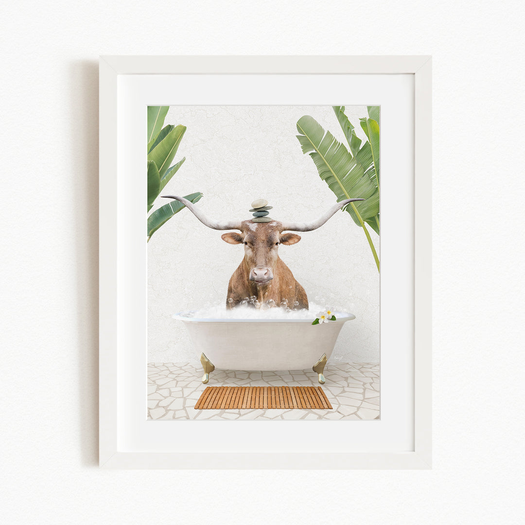 A framed image depicting a cow sitting in a bathtub filled with water, surrounded by tropical plants.