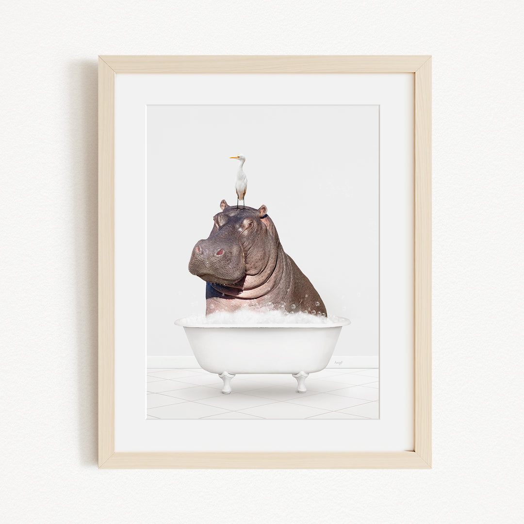 A framed image depicting a hippopotamus sitting in a bathtub, with a seagull perched on its head.