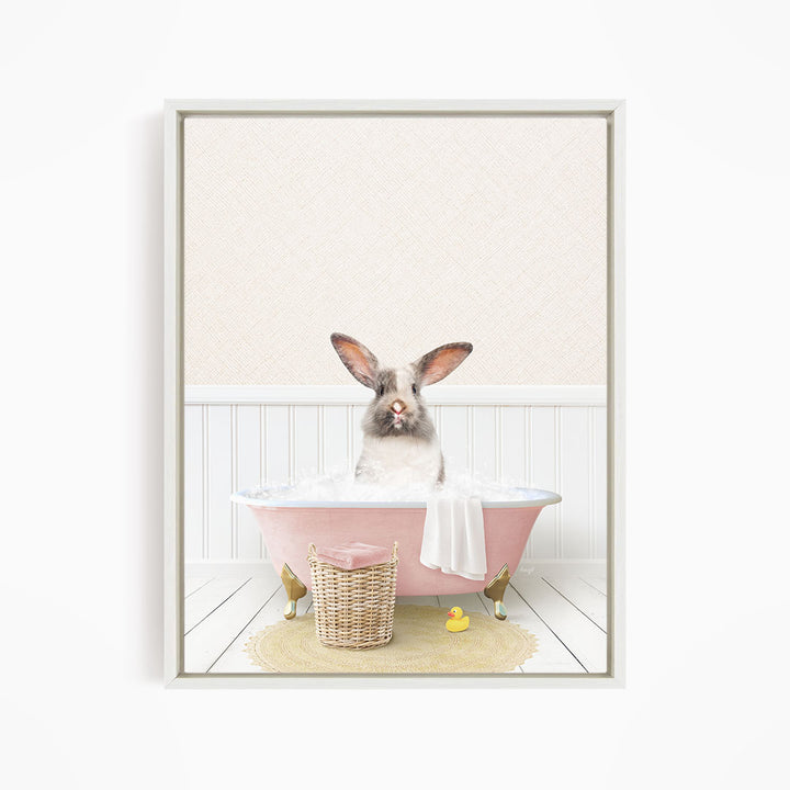A white rabbit sitting in a pink bathtub filled with bubbles, surrounded by a yellow rubber duck and a wicker basket.