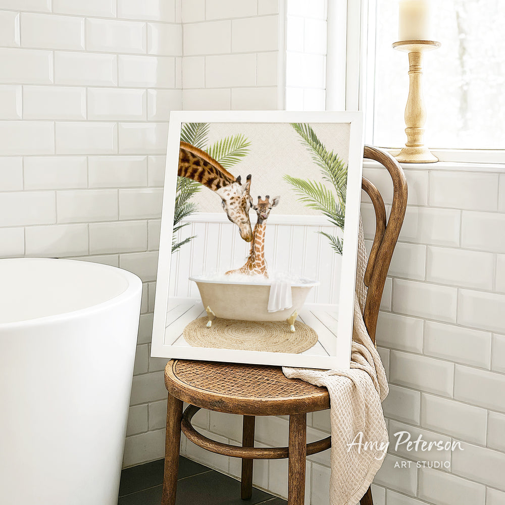 A framed image of two giraffes sitting in a bathtub, surrounded by tropical plants, is displayed on a wooden chair in a bathroom setting.
