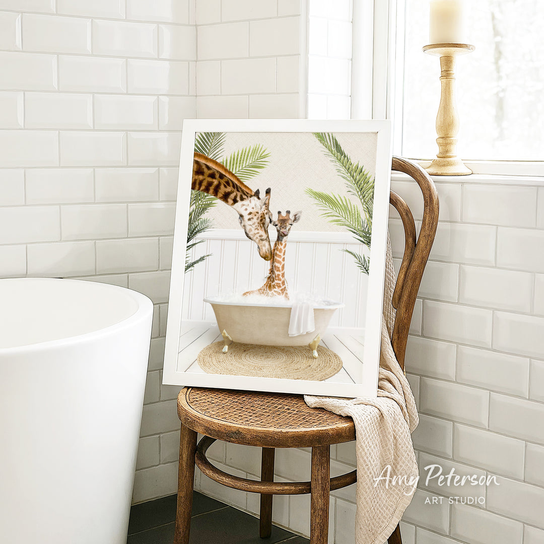 A framed image of two giraffes sitting in a bathtub, surrounded by tropical plants, is displayed on a wooden chair in a bathroom setting.