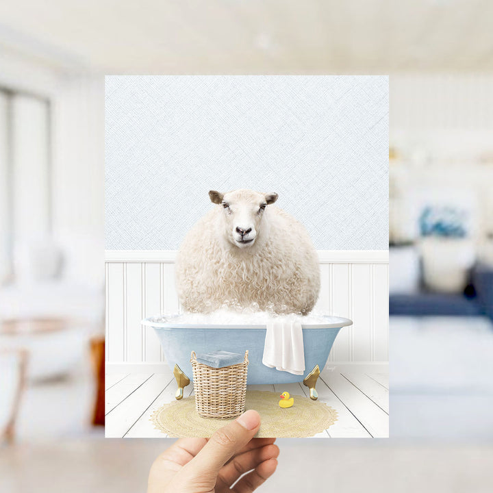 A fluffy white sheep sits in a blue bathtub filled with bubbles, surrounded by a yellow rubber duck and a white towel.