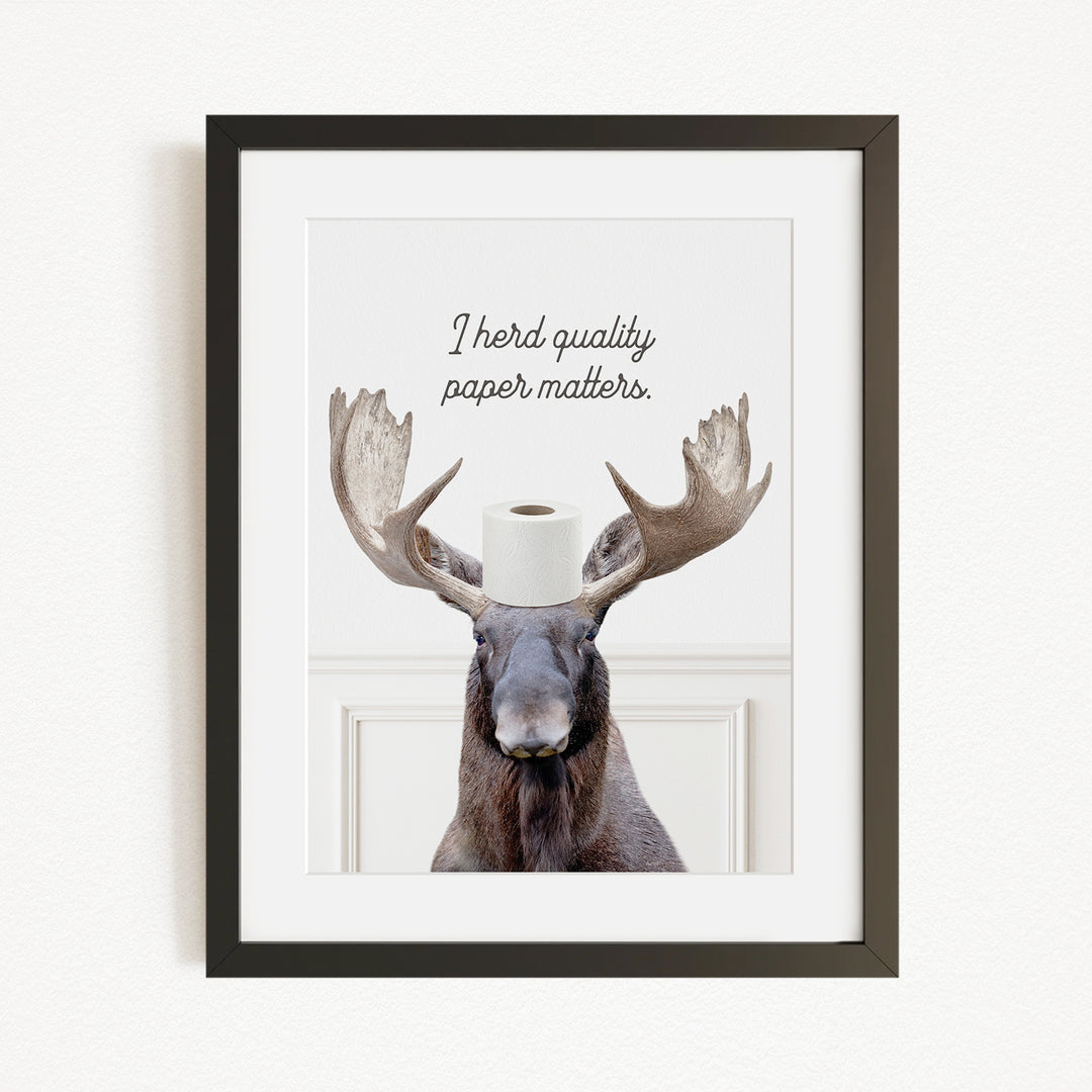 A framed image of a moose with a roll of toilet paper on its head, accompanied by the text "I herd quality paper matters."