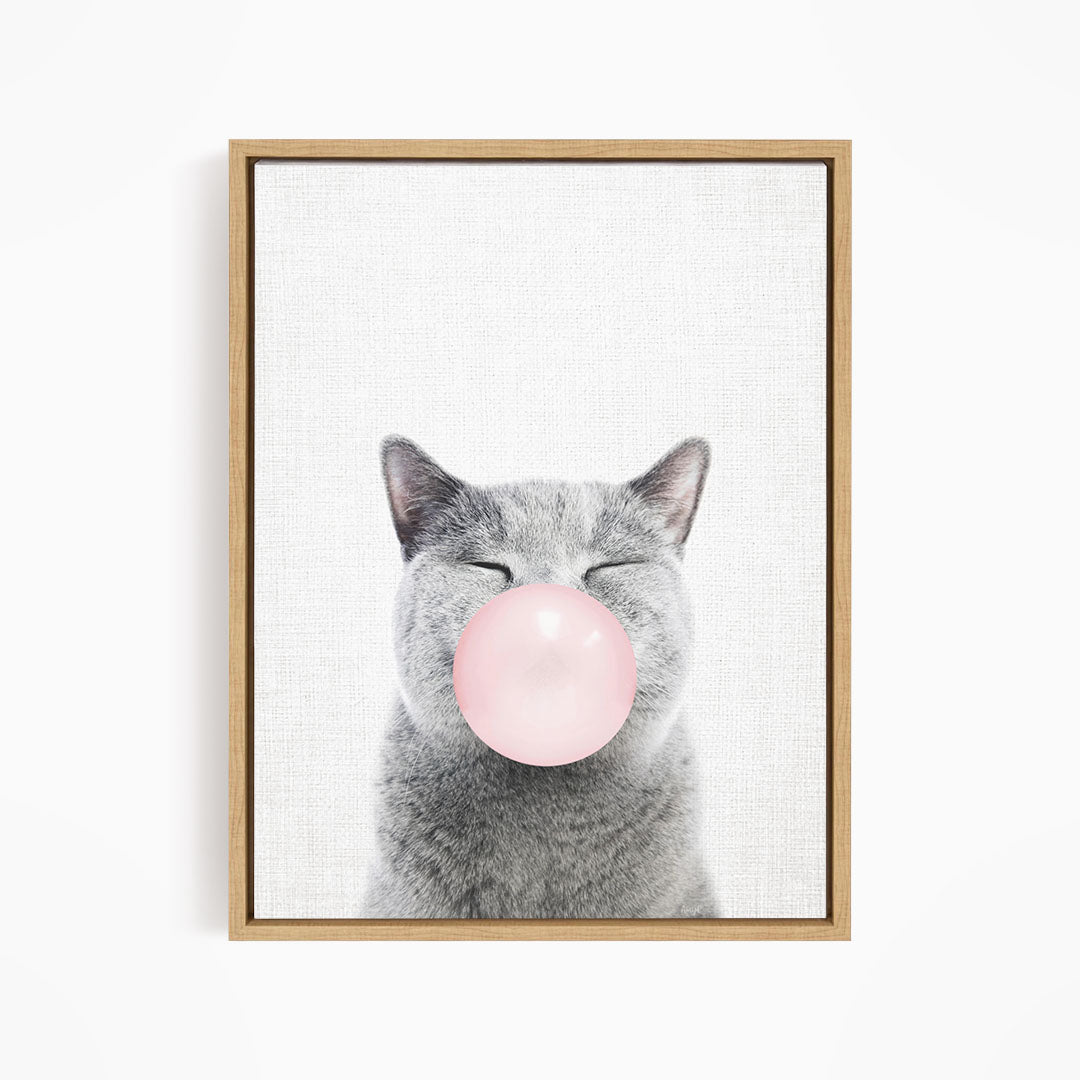 A gray cat blowing a pink bubble with its mouth.
