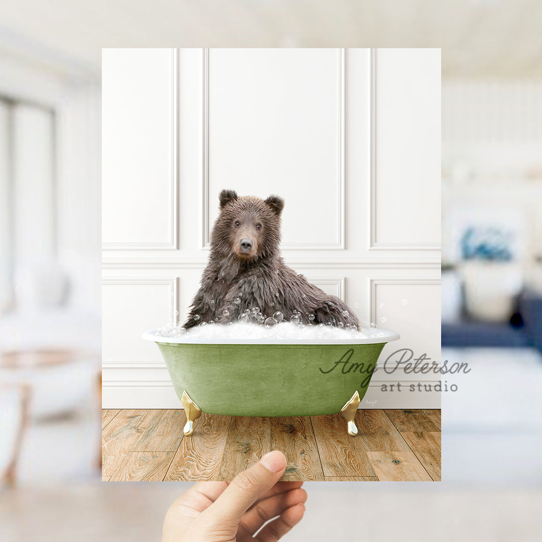 a hand holding a photo of a bear in a bathtub