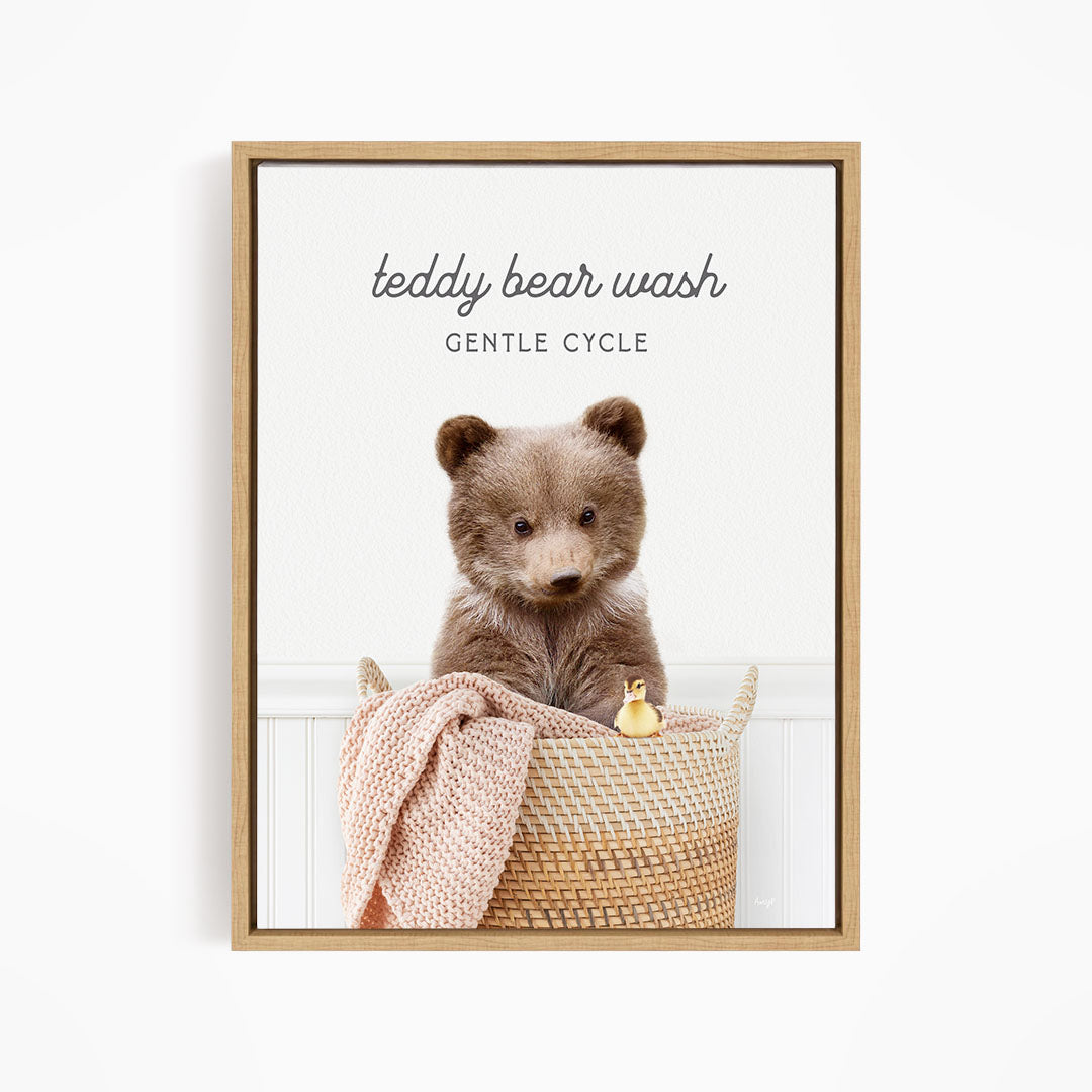 A teddy bear sitting in a woven basket, with a blanket and a small toy duck nearby.