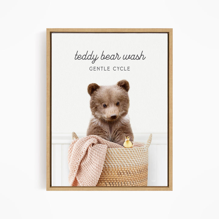 A teddy bear sitting in a woven basket, with a blanket and a small toy duck nearby.