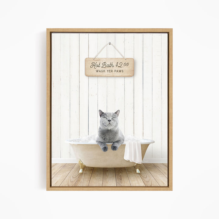 A gray cat sitting in a white bathtub, with a wooden sign above that reads "Hot Bath $2.00 WASH YET Paws".