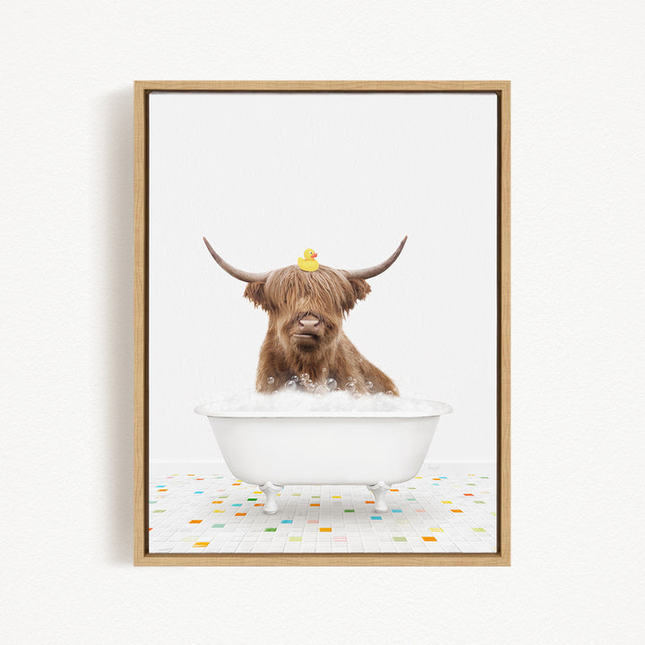 A brown cow with long horns is sitting in a white bathtub filled with bubbles, with a rubber duck perched on its head.