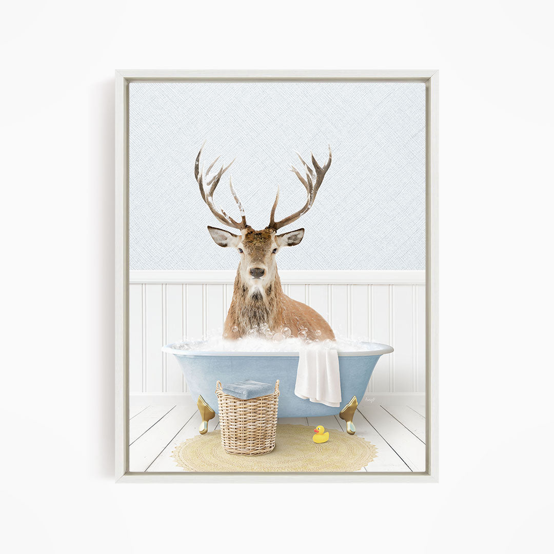 A deer with antlers is sitting in a bathtub filled with water, surrounded by a yellow rubber duck and a wicker basket.