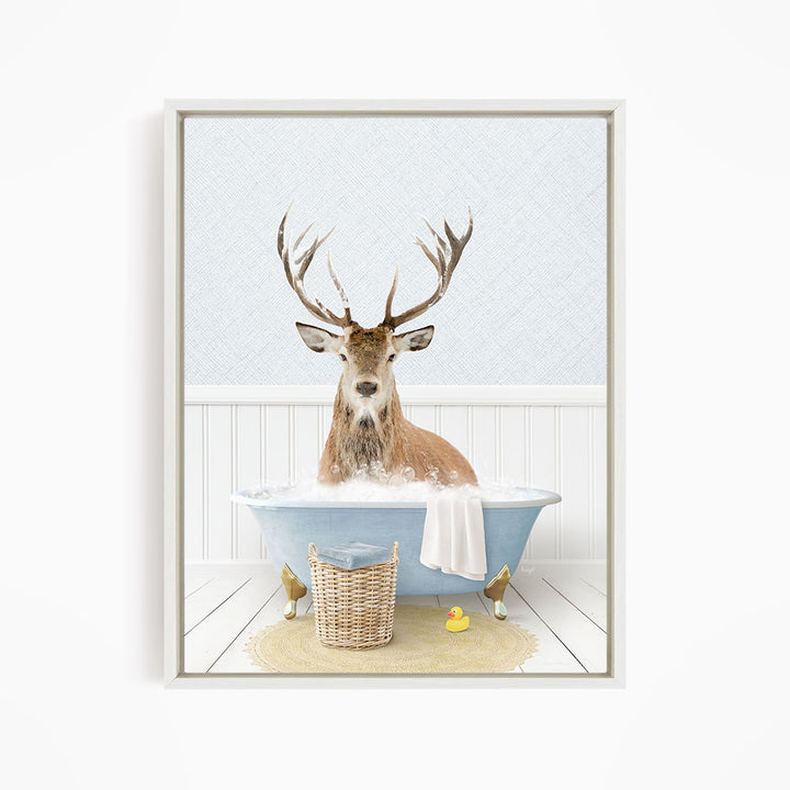 A deer with antlers is sitting in a bathtub filled with water, surrounded by a yellow rubber duck and a wicker basket.