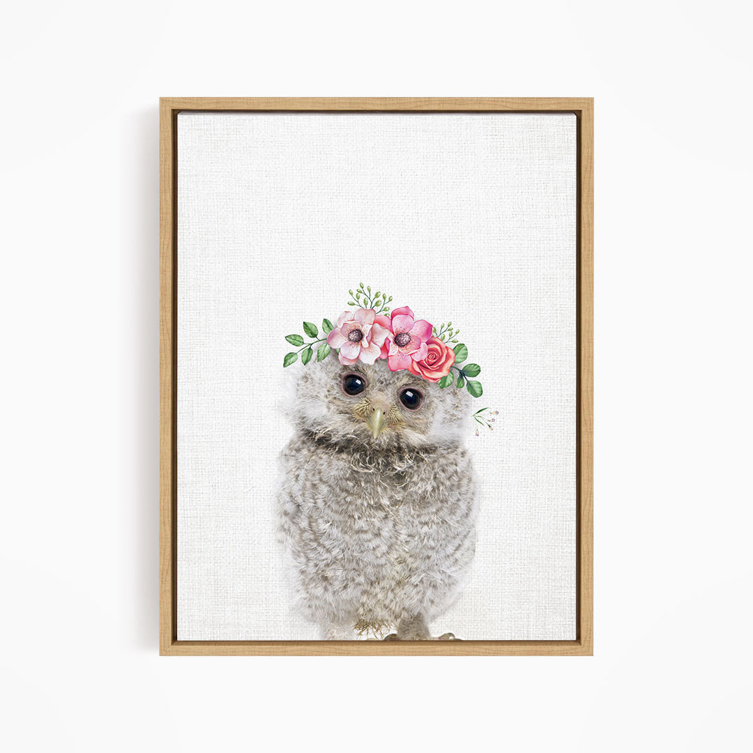 A framed print of a fluffy gray owl wearing a floral crown of pink and white flowers.