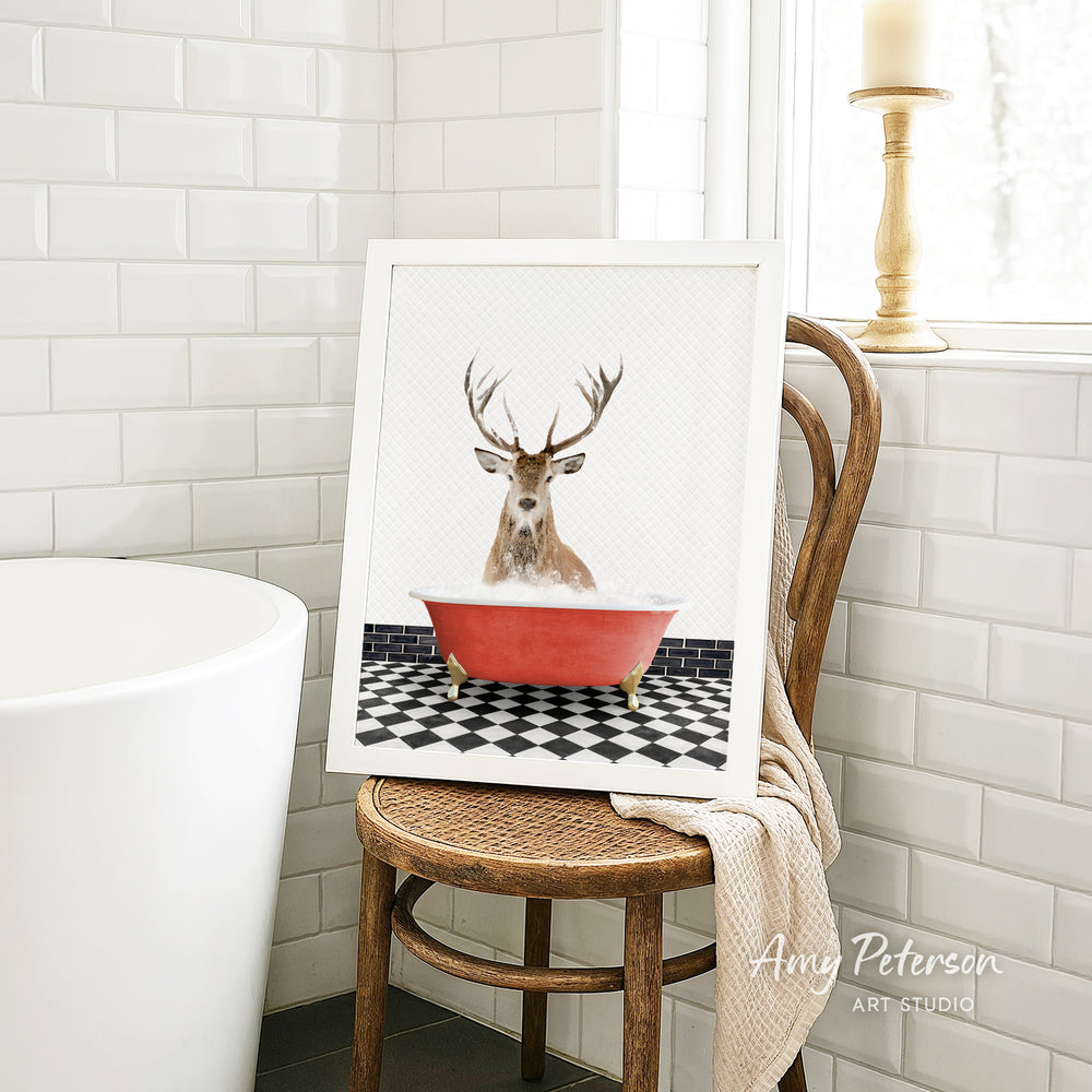 A framed image of a deer with antlers sitting in a red bathtub, surrounded by a black and white checkered floor.