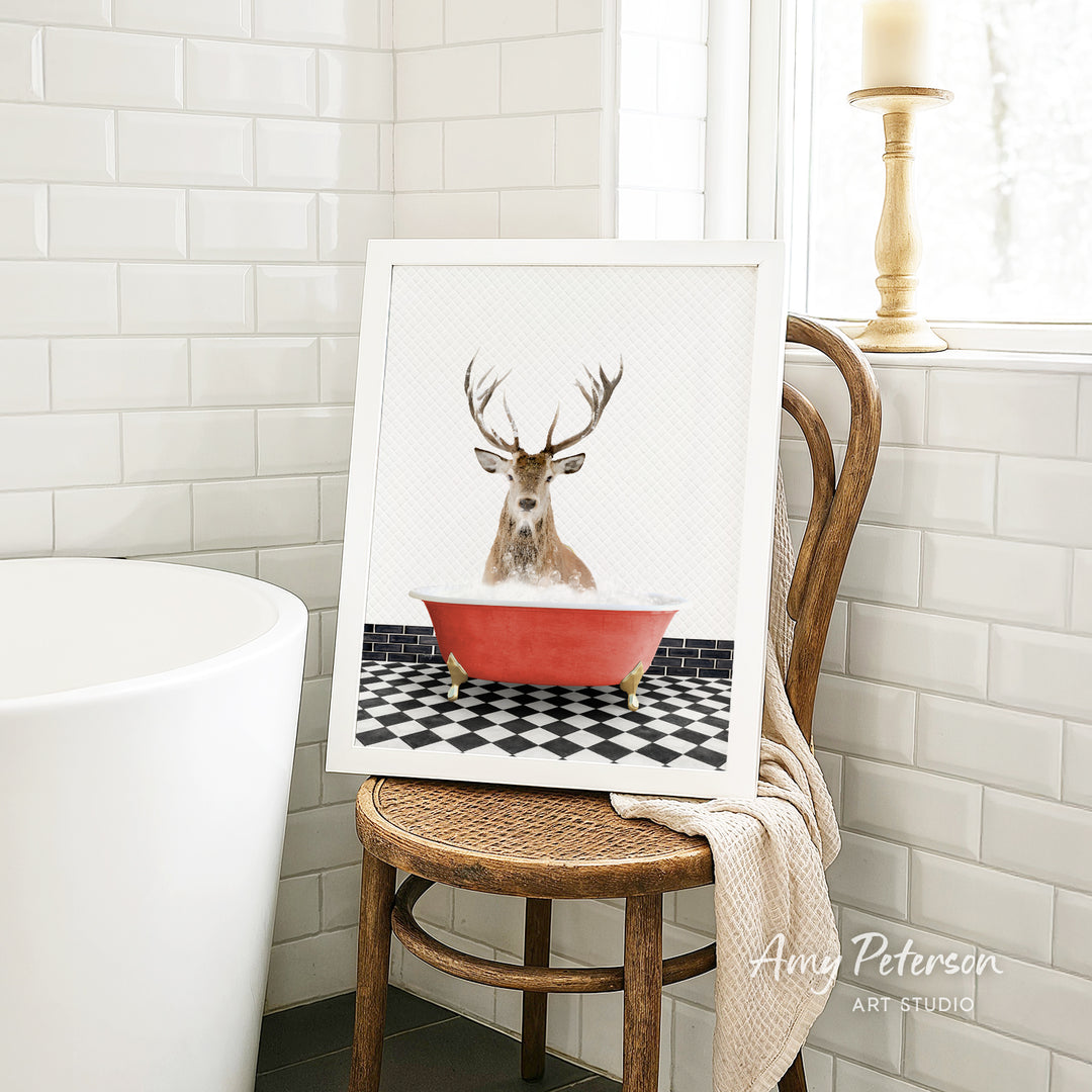 A framed image of a deer with antlers sitting in a red bathtub, surrounded by a black and white checkered floor.
