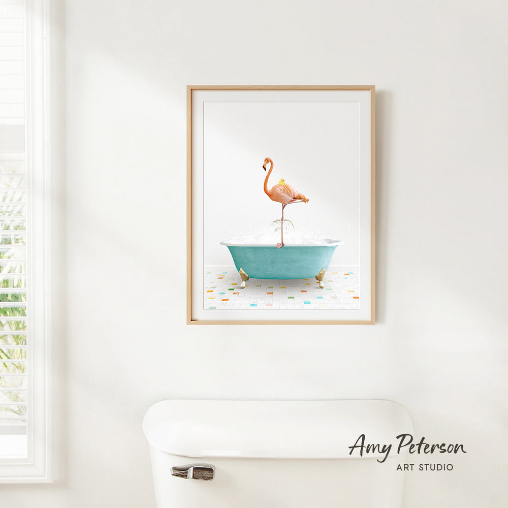 A framed print of a flamingo standing in a blue bathtub is hanging on a white wall.